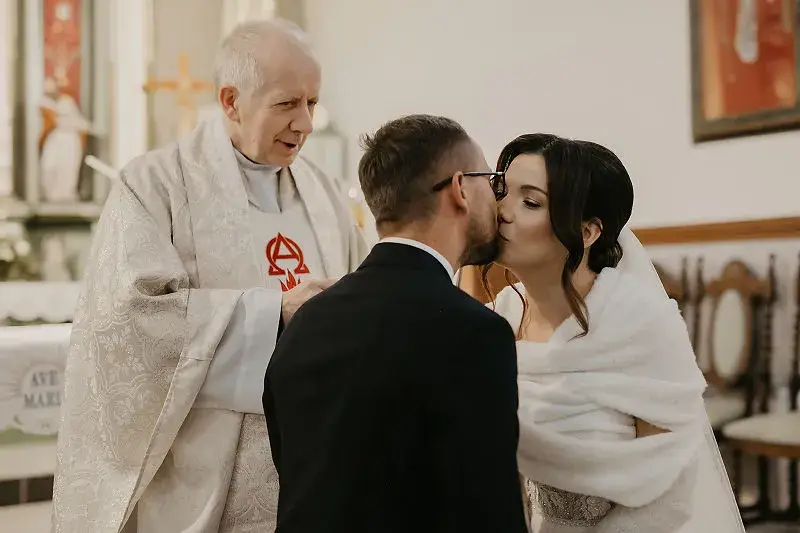 Para Młoda całująca się po ceremonii ślubnej w kościele
