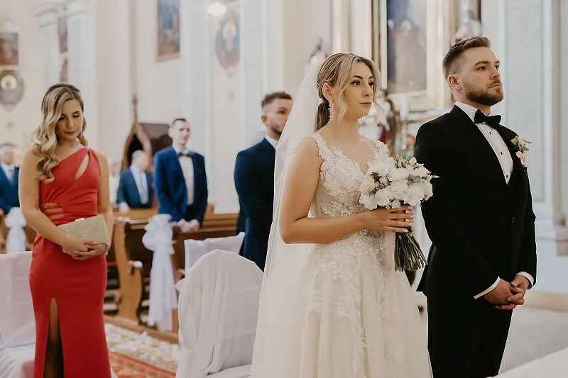 Para młoda podczas ceremonii ślubnej w kościele, z gośćmi w tle Para młoda podczas ceremonii ślubnej w kościele, z gośćmi w tle